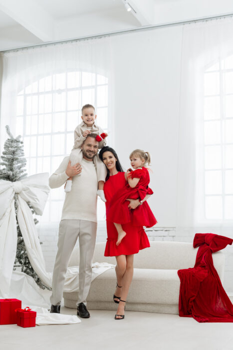 Familie mit Eltern und Kindern beim Weihnachtsfotoshooting in einem hellen Studio.